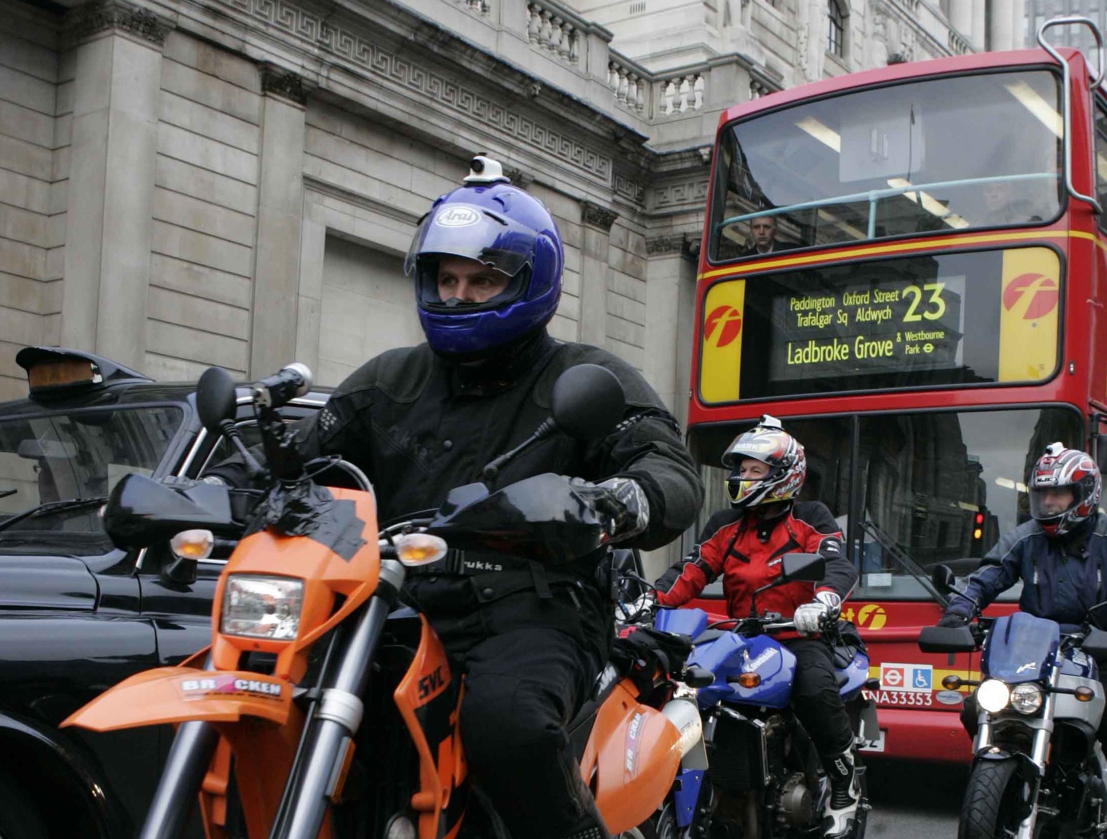 three motorcyclists with bus and taxi in London